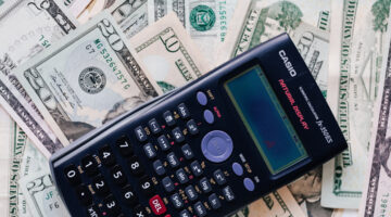 calculator placed over a stack of USA dollars