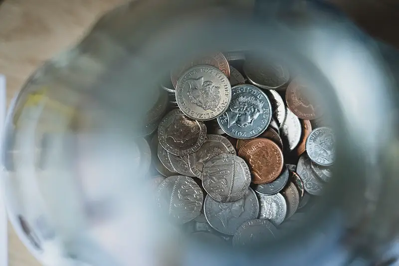looking down into money jar full of coins – savings