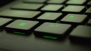 Close up of black keyboard with green back light. Focused on Microsoft window key