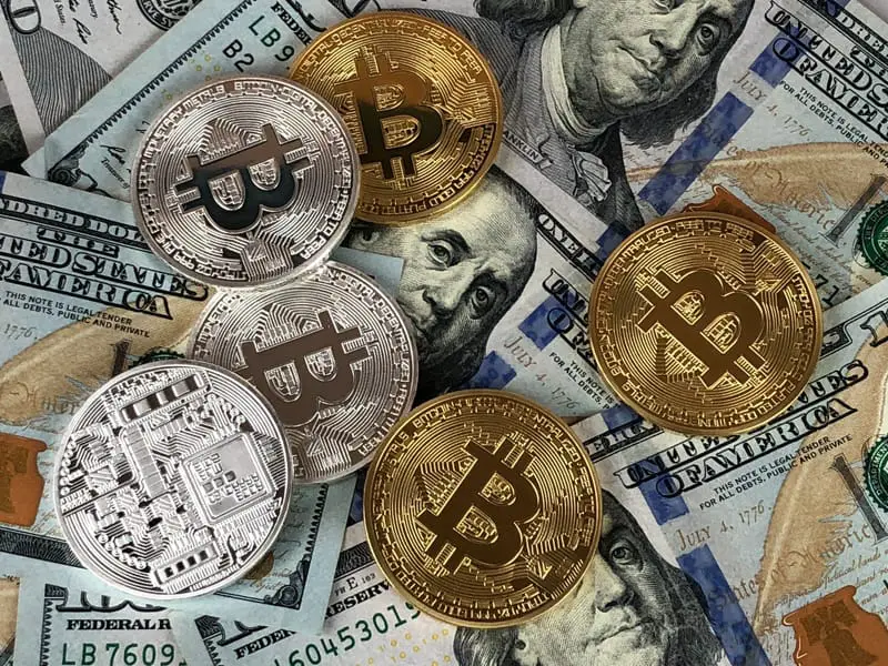 silver and gold coins – cryptocurrency on top of US dollar bills