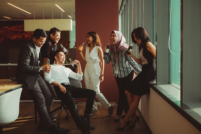 A group of people laughing while having drinks 