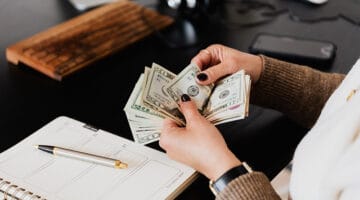 Woman on her desk counting dollars on her hand
