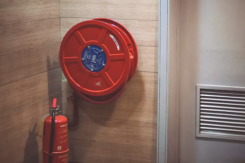 red fire extinguisher beside red hose reel fixed to the wall