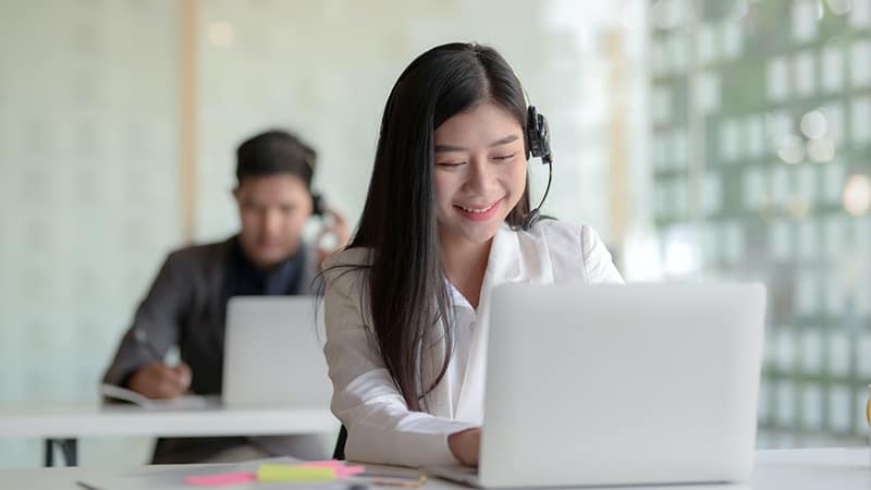 Smiling woman in headphones using laptop