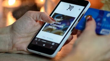 Person using black and white smartphone and holding blue card