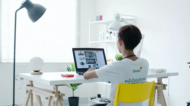 A young person sitting in front of laptop on white table