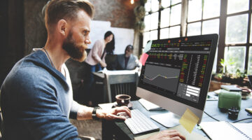 A man in blue sweat shirt working in front of computer