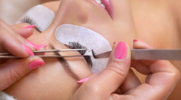 Beautiful Woman with long eyelashes in a beauty salon. Eyelash extension procedure by Eyelash Artist Entrepreneur. Lashes close up.