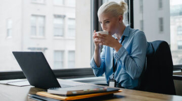 Female manager drinking coffee at her desk in the workplace