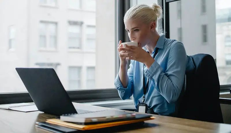 Female manager drinking coffee at her desk in the workplace