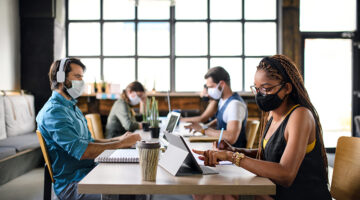 Business people with face masks indoors in office, back to work after coronavirus lockdown.