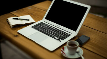 Silver MacBook and a cup of coffee on the top of the wooden table