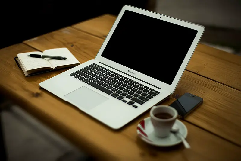 Silver MacBook and a cup of coffee on the top of the wooden table
