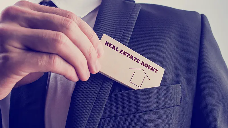Person putting calling card of real estate agent on his pocket