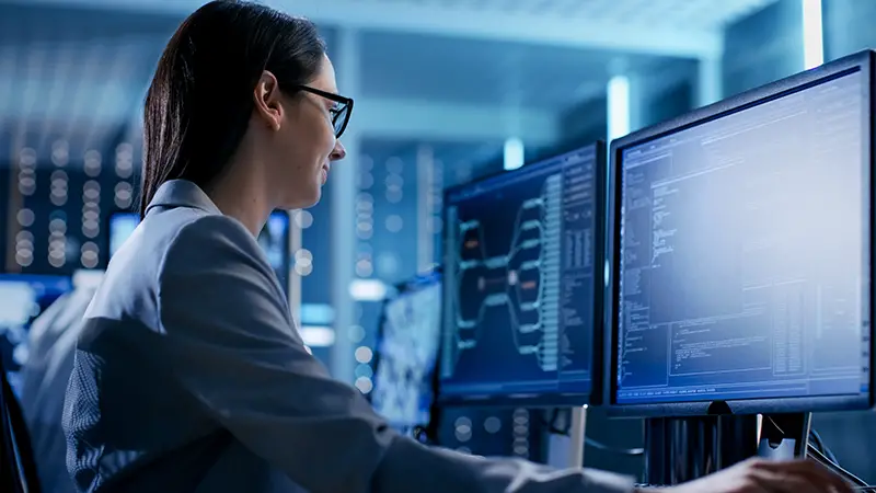 Woman wearing eyeglasses working in front of computers