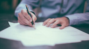 A man signing a documents on the table