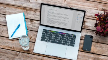 Silver macbook and smartphone on the top of wooden table