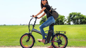 A smiling woman with electric bicycle in the park – e-bike