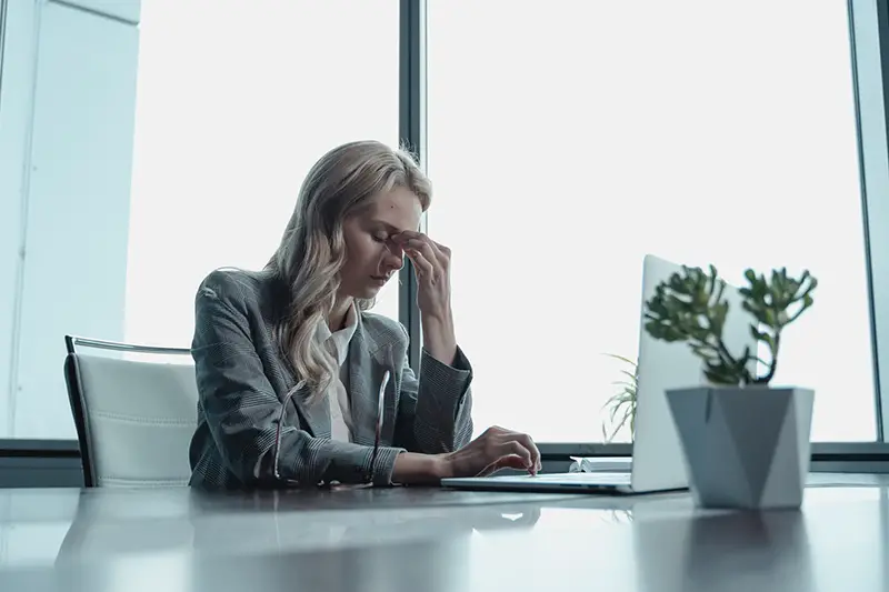 Woman with headache while working on her laptop
