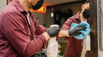 Salon worker wearing mask and gloves sanitizing surfaces using salon disinfectant
