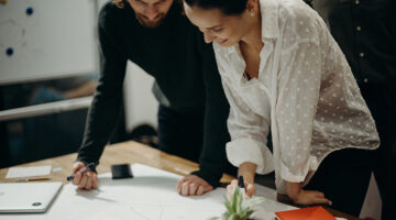 Man anad woman staring at white board on top of the table