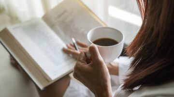 Woman holding coffee while reading