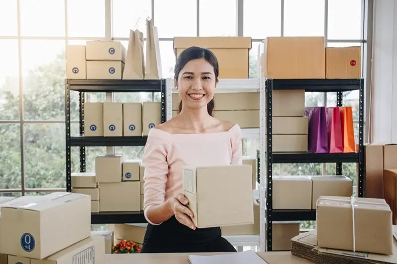 Woman holding a box and packing up office for relocation.