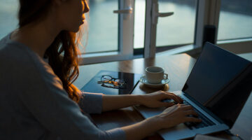 Woman sitting beside the table while working on her laptop