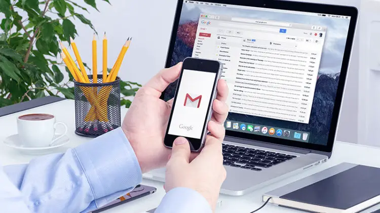 Man holding smartphone with Gmail icon on screen