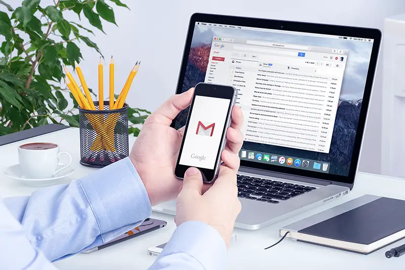 Man holding smartphone with Gmail icon on screen