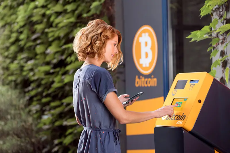 Woman in front of Bitcoin ATM for crypto currency.