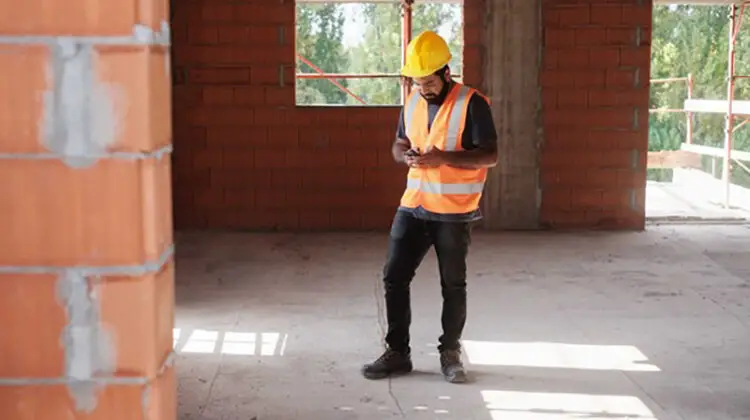 Man wearing helmet using mobile phone inside construction building