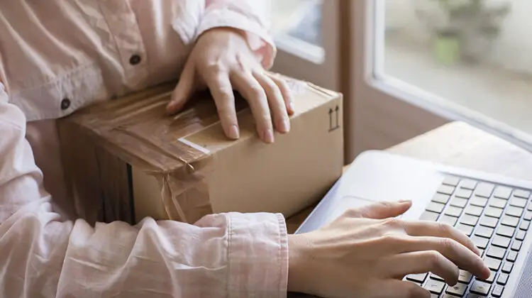 A close up of a female hand with a keyboard and a parcel, buying things on the internet