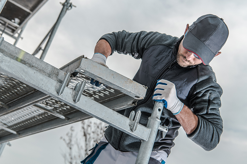 Caucasian Construction Worker Installing Scaffolding Elements