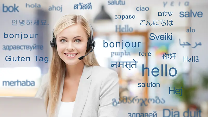 translation, business and technology concept - smiling female translator or operator in headset at office over greeting words in different foreign languages