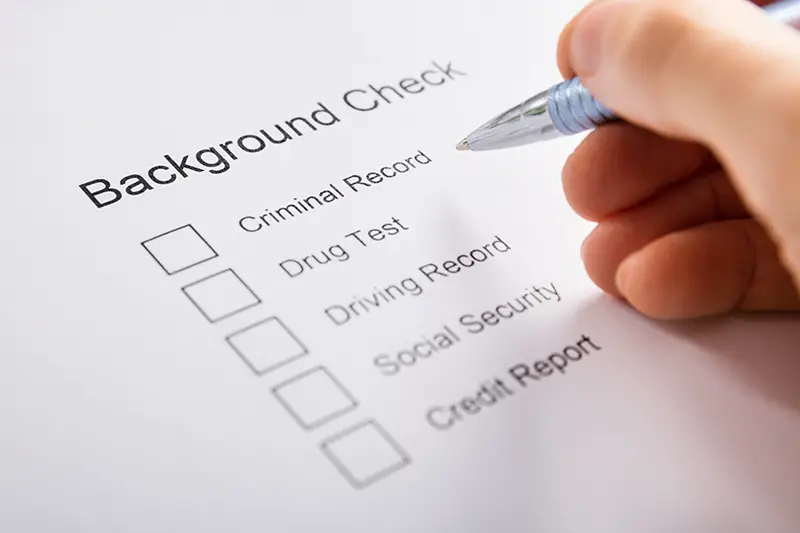 Close-up Of Person Hand Filling Background Check Form