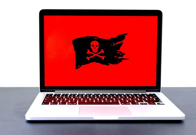 laptop displaying a black pirate flag on a red screen