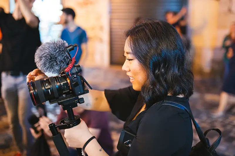 Asian woman holding black DSLR camera