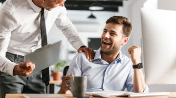 Happy emotional men colleagues in office working with computer.