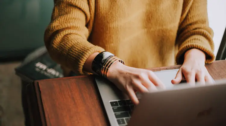 Person wering orange sweatshirt using laptop computer