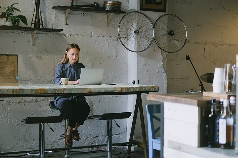 Employee sitting on a stool and working on a laptop
