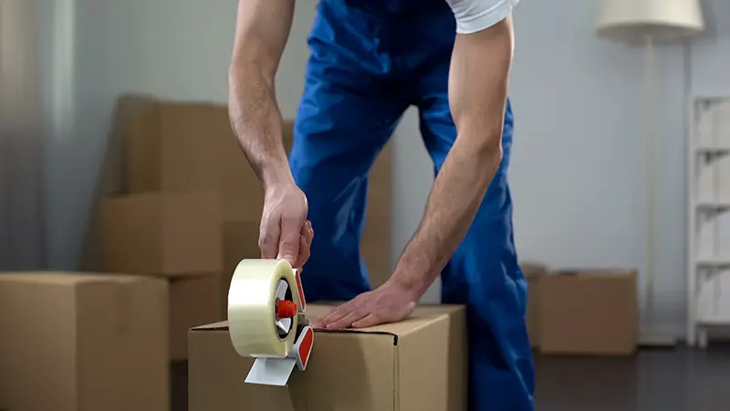 Moving company worker packing cardboard boxes