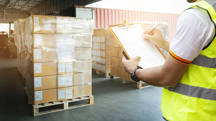 Man holding clipboard while checking items in a warehouse