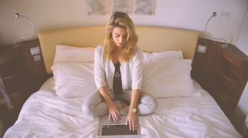 Woman working on her laptop on her bed