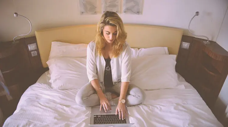 Woman working on her laptop on her bed