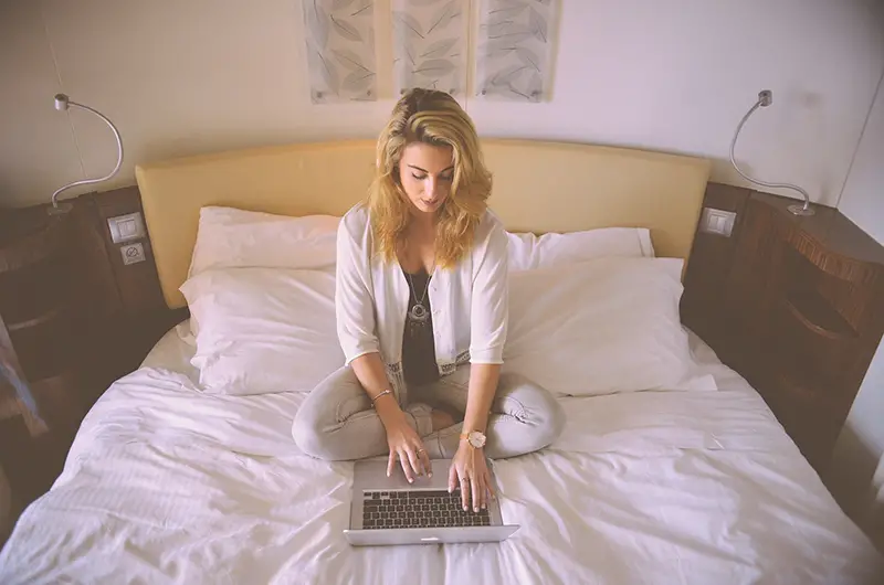 Woman working on her laptop on her bed