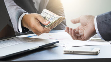 Two businessmen give and take US dollar banknote