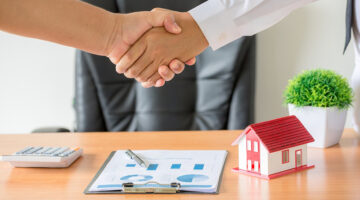 Side view hands of agent and client shaking hands after signed contract