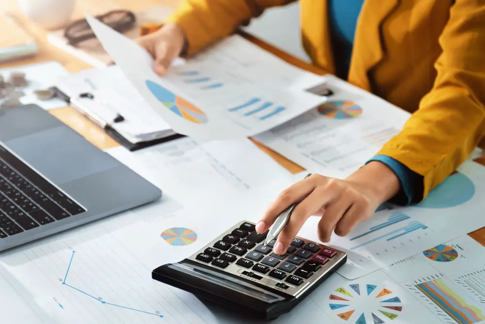 woman using calculator and looking at financial charts