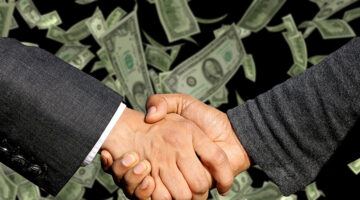 Two businessman handshaking with dollar notes on background